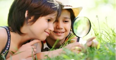 two children using a magnifying glass exploring outside