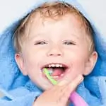 toddler boy smiling and brushing his teeth