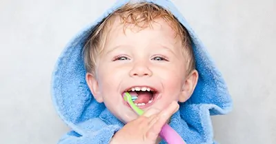 toddler boy smiling and brushing his teeth