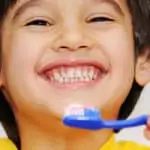 young boy smiling and brushing his teeth