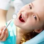 smiling girl in chair receiving a dental exam