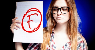 frowning woman holding sign that says "F"