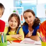 four children in classroom smiling