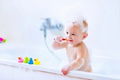 Baby brushing teeth in bathtub