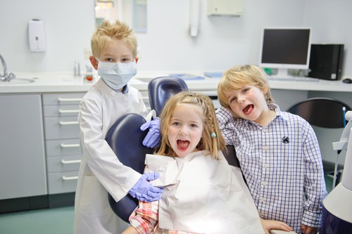 three young kids in dental office playing dentist