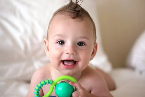 baby smiling holding toy