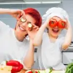 mother and daughter having fun with vegetables in kitchen