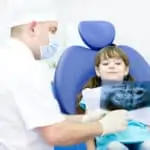 little girl and dentist looking at x-ray