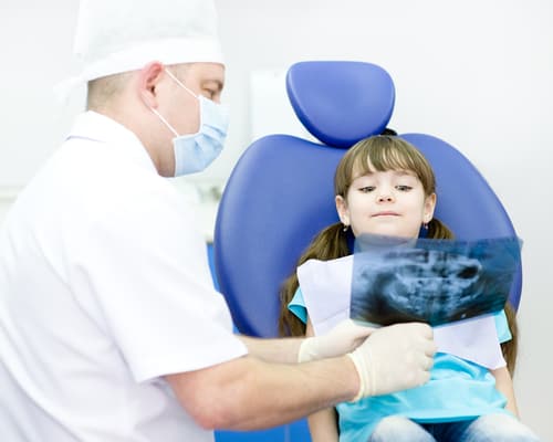 little girl and dentist looking at x-ray