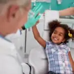 little girl high-fiving dentist in dental chair