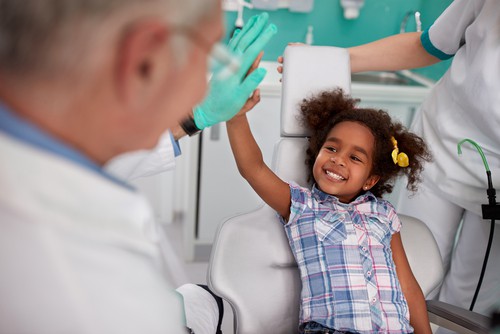 little girl high-fiving dentist in dental chair