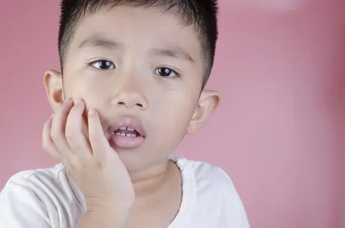 little boy holding mouth with toothache