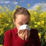 Girl sneezing with tissue - field of flowers in background