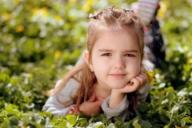 Little girl smiling, lying in field