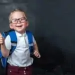 young boy with backpack giving thumbs up