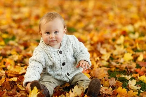 baby outside sitting in leaves