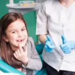 little girl with missing tooth in dental chair